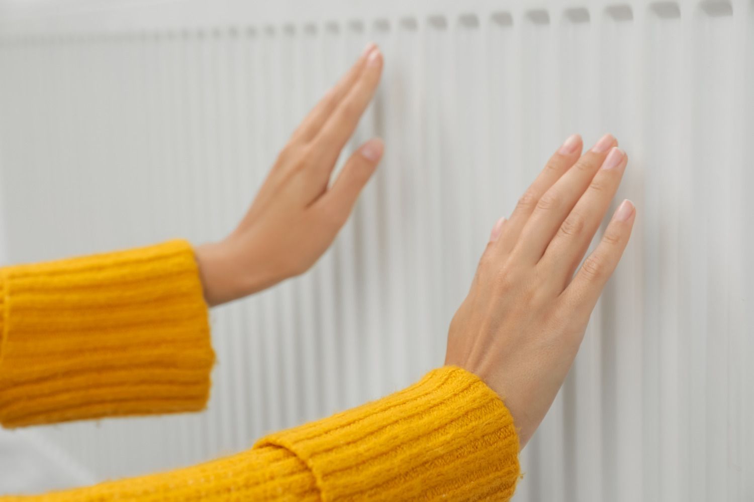 Lady warming her hands on a radiator.